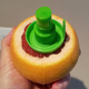 hand holding up a grapefruit with the end cut off and the citrus sprayer screwed in, with outlet on wall visible in background